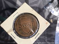 Front side of the token with Ford shield logo and years 1903-1933