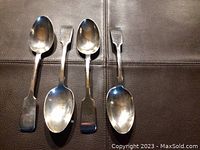 Four large sterling silver serving spoons laid out flat on surface showing overall condition and design.