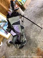 Full view of golf bag standing upright filled with various golf clubs, showcasing the Wilson brand bag in purple, white, and black colors.