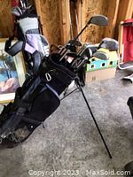 Photo of a set of men's right-handed golf clubs in a black and purple golf stand bag placed in a garage.