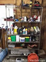 Metal wire shelving unit with four shelves on caster wheels in a workshop with various items on shelves not included in sale.