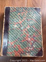 Photo of the hardcover binding of the Punch Cartoon Almanac 1862 showing marbled cover and black spine with wear.