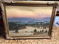 Front view of the winter landscape oil painting in a decorative gold frame, showing snow-covered fields, trees, and a distant horizon at sunset.