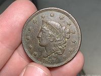 Front side view of 1837 Liberty Head Large Cent in hand showing LIBERTY head, stars, and date