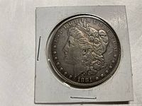 Obverse side of the 1881 Morgan Silver Dollar showing Lady Liberty's profile in a protective holder.
