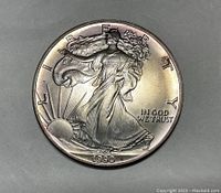 Obverse side of 1990 Walking Liberty silver dollar coin showing Lady Liberty walking with sun and date 1990
