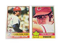 Photo of front side of two vintage 1976 Topps baseball cards showing Carlton Fisk in Red Sox uniform and Pete Rose in Reds uniform.