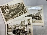 Three black and white antique train photographs displayed overlapping on a flat surface, showing front and side views of steam trains.
