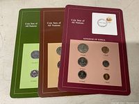 Three coin sets from different countries mounted on cards labeled 'Coin Sets of All Nations'. The visible coins belong to the Kingdom of Tonga set.