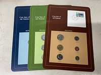 Three mounted coin sets on cards labeled 'Coin Sets of All Nations' in blue, green, and brown for Republic of China, Socialist Republic of Romania, and Malaysia.