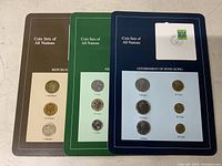 Set of three vintage international coin sets from Republic of Finland, French Republic, and Government of Hong Kong displayed on cards with denominations visible.