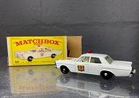 Side view of the white Lesney Matchbox police car with original yellow and blue box behind it showing the model number 55 and police car graphic.