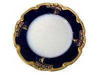 Top view of a round decorative dish with navy blue border and ornate gold embellishments showing no damage.