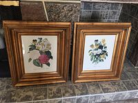 Two floral prints in golden wood frames placed side by side on tiled floor. Each frame measures about 10.25 by 12.25 inside the frame.