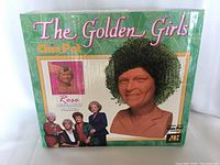 Top view of boxed Golden Girls Rose Chia Pet showing brand, character, and imagery of the product with leafy print background.