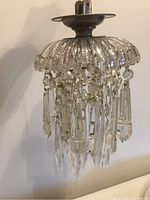 Full view of small crystal chandelier light fixture showing hanging crystals and ribbed glass top.