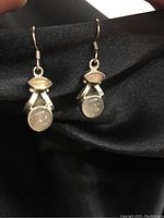Close-up image of the pair of sterling silver fish hook earrings with round rose quartz stones.