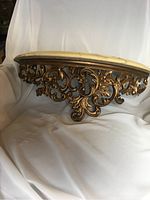 Side angle of the floating wall shelf showing the detailed carved wooden support base and the heavy faux marble top.