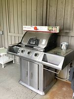 Full view of Vermont Castings Signature Series propane BBQ grill with three control knobs, side shelf and rotisserie box on top.