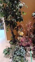 Overall view of large faux tree in pot with multiple floral arrangements around base