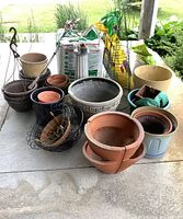 Overall view of garden supplies including various plant pots, peat moss bags, black wire baskets, and garden accessories.