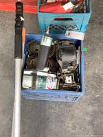 Full view of crate containing Hitachi coil nailer, coils of nails, long brush and squeegee.