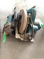 Makita corded skill saw showing metal blade guard with rust and turquoise motor housing, cord visible.