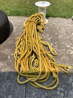 Loose yellow nylon rope bundle with frayed ends visible on concrete ground.