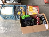 Wide view of lot with cardboard box of totes and three crates of sealed cable ties