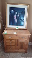 Full view of wooden wash stand with framed print artwork on top