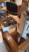 White Xbox 360 console standing vertically on wooden table with visible power cord next to it.