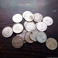 Pile of coins on wood surface showing obverse and reverse sides of multiple 50 cent coins.