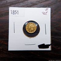 Obverse of the 1851 Liberty Head gold dollar showing Liberty head wearing coronet with 13 stars and date in cardboard flip.