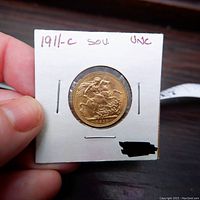 Reverse of coin in cardboard flip holder marked '1911-C SOV UNC', showing Saint George and the dragon design