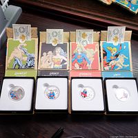 Four opened display boxes showing four colorized silver coins and matching box art