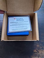 Opened cardboard box showing Fanatics Authentic hologram verification card inside.
