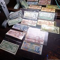 Photo showing various Canadian bank notes including $1, $2, and $5 bills arranged on table with some in holders.