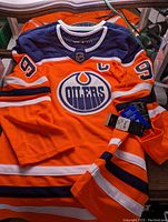Front view of the orange and navy Edmonton Oilers jersey with #9 on sleeves, captain patch and Adidas collar with tags attached