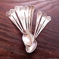 Twelve Danish silver tea spoons arranged together, showing floral detail on handles.