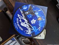 Top view of hockey puck showing autographed image of Auston Matthews with Rocket Richard Trophy and signature.