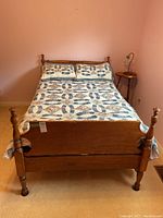 Front view of solid wood bed with spindle posts and quilt with matching pillows