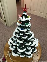 Full view of the vintage ceramic Christmas tree lit with various colored bird-shaped light covers and red star topper.