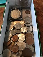 A box containing various Canadian and UK coins including copper and silver colored coins.