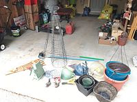 Photo of assorted garden items including trellis, tomato cages, planters, bird feeders, bird houses, and garden tools on garage floor.