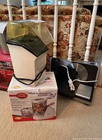 Lot showing the Betty Crocker mini blender/chopper on its original box and the Sunbeam popcorn popper behind with the butter melter on top, the appliances are on a carpeted floor.