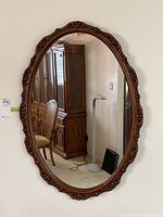 Full frontal view of the oval mirror hung on the wall showing its size and reflection of room.