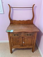 Front view of the vintage wooden wash stand showing drawer, cupboard, and backsplash.