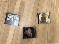 Top view of three Leonard Cohen CD jewel cases showing front cover art including Songs of Love and Hate, Various Positions, and The Best of Leonard Cohen.