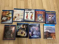 Clear image of all 9 Blu-Ray DVDs arranged on a wooden floor showing title and cover art.