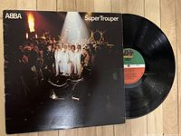 Front cover of ABBA Super Trouper vinyl record partially open showing black vinyl disc.
